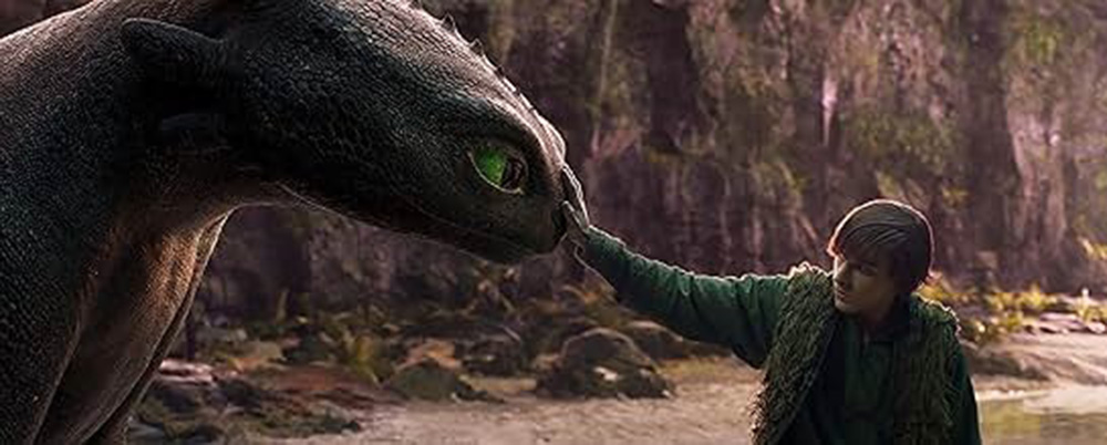 Hiccup gently touches Toothless' head in a forest setting.