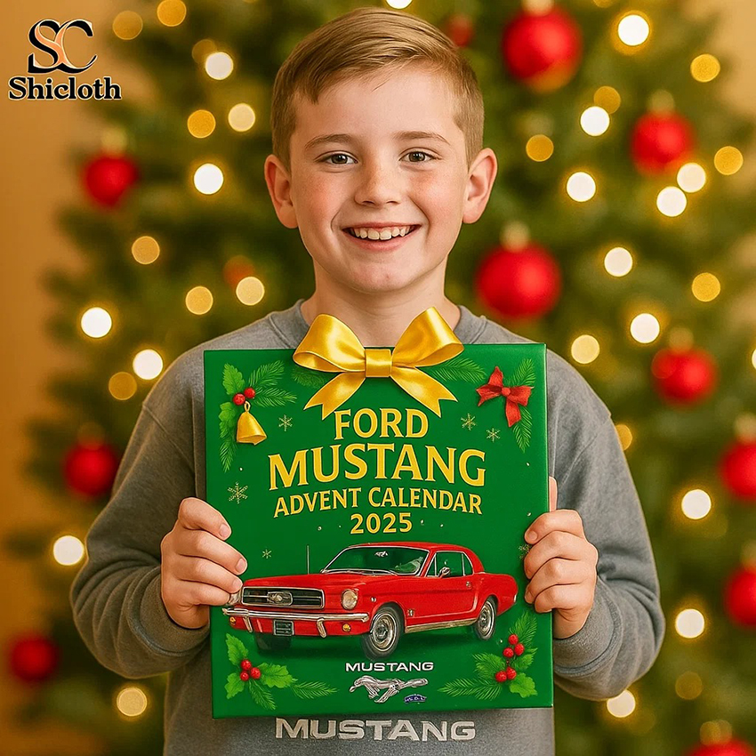 A young boy smiling while holding a Ford Mustang Advent Calendar 2025 with a red Mustang car on it in front of a Christmas tree.