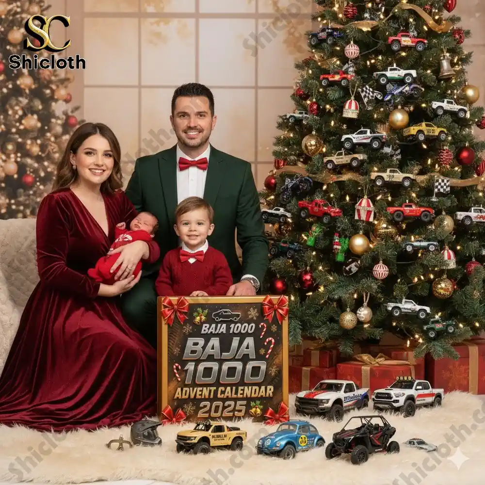 A smiling family in festive attire poses beside a decorated Christmas tree with the Baja 1000 Advent Calendar 2025 and toy cars displayed in front!