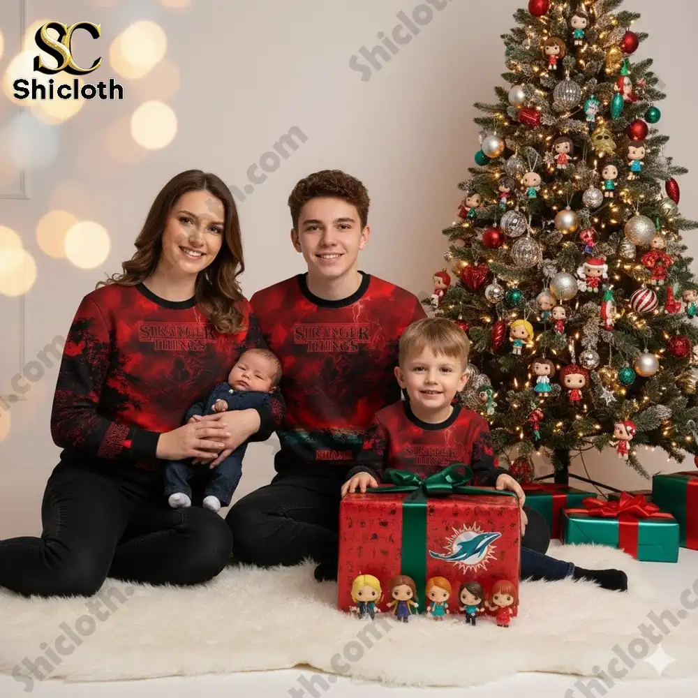 A family wearing matching Miami Dolphins x Stranger Things sweaters posing by a decorated Christmas tree.