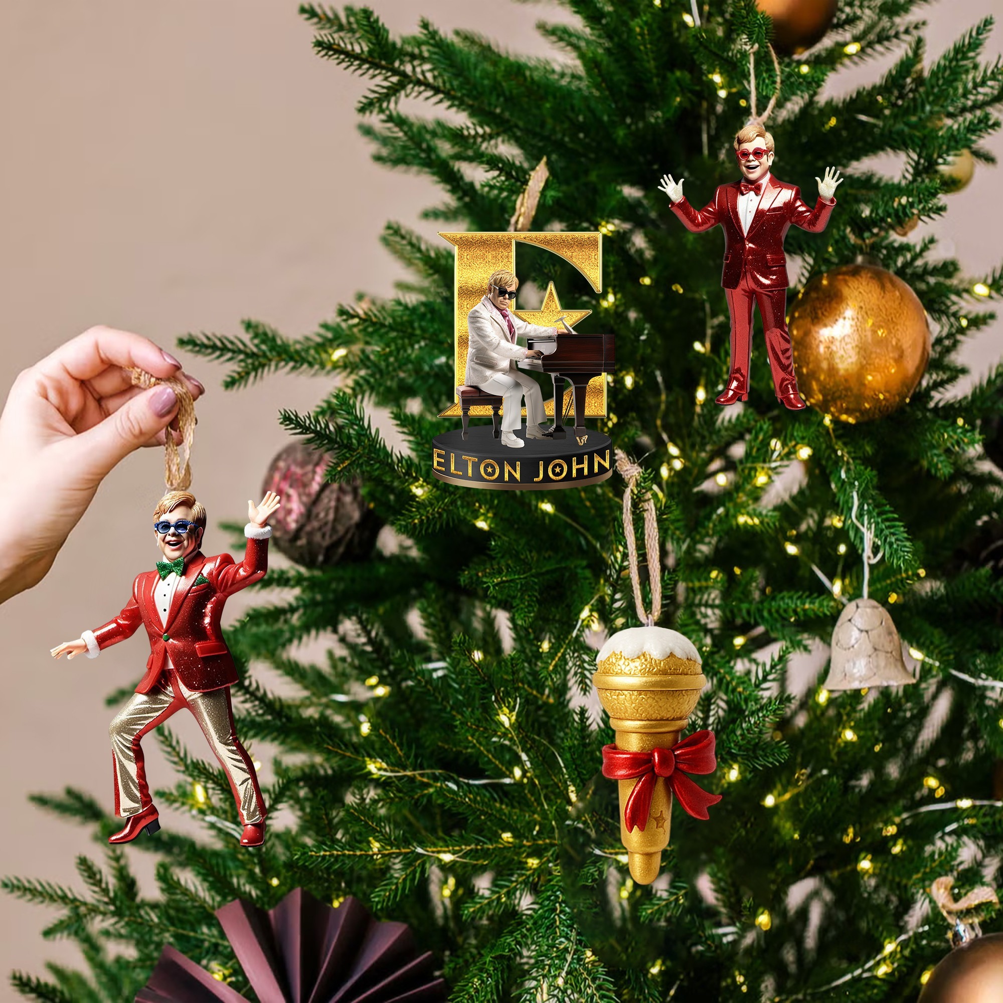 Elton John Advent Calendar 2025 4 Hands hanging Elton John themed ornaments on a Christmas tree with festive lights.