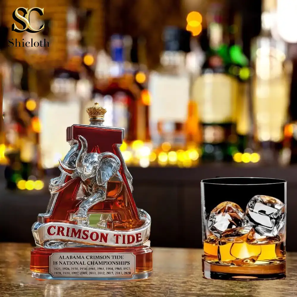 A crimson Alabama Crimson Tide liquor bottle shaped like the letter A placed on a bar counter beside a glass of whiskey.