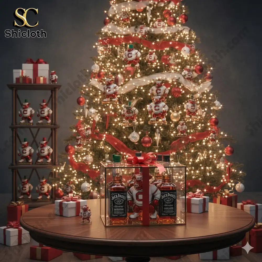 A lit Christmas tree with red and white mascot ornaments stands behind a glass boxed whiskey gift set on a round table!