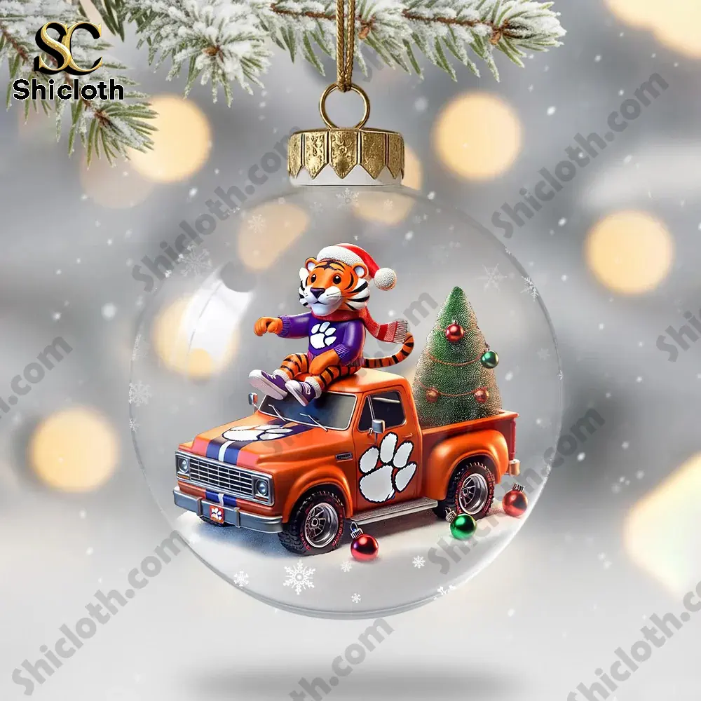 A clear ornament featuring a cartoon tiger sitting on an orange truck with a tree.