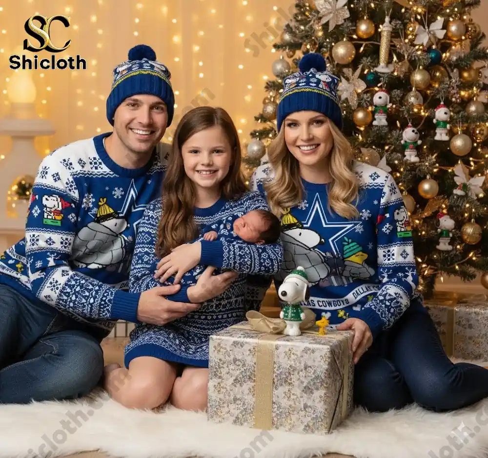 A family of four in matching Dallas Cowboys Snoopy Christmas sweaters sitting together by a Christmas tree, with the newborn in the arms of the mother.