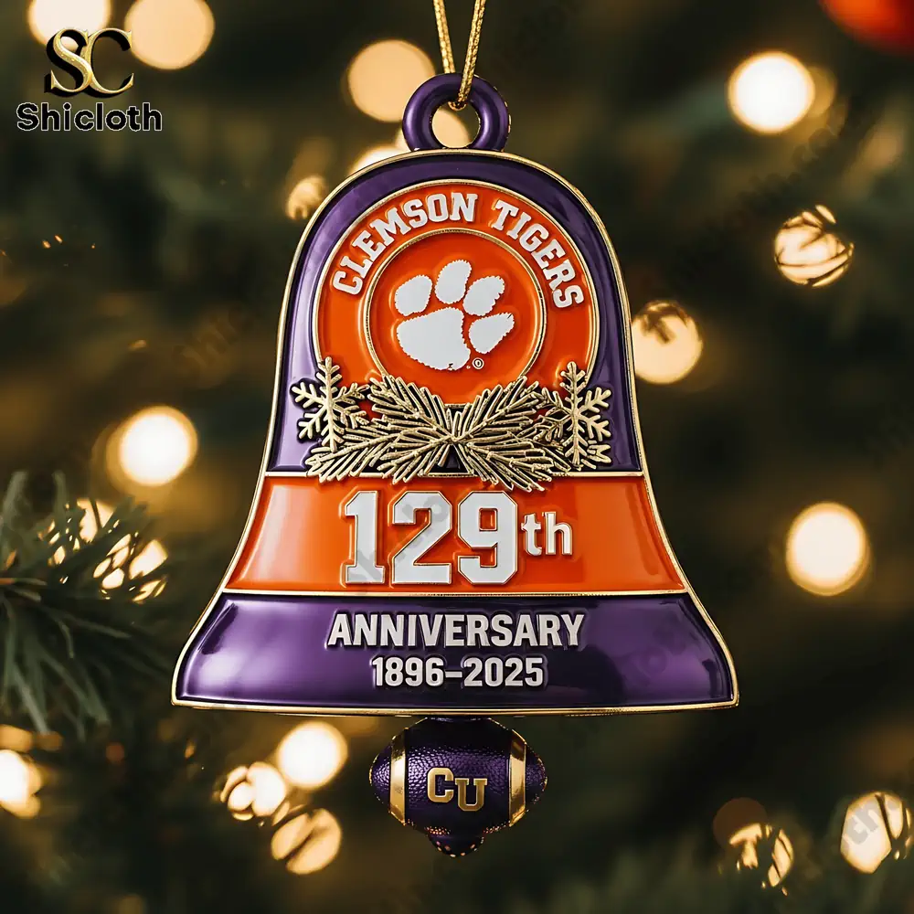 Close up of a Clemson Tigers 129th anniversary Christmas bell ornament in orange and purple hanging on a tree.