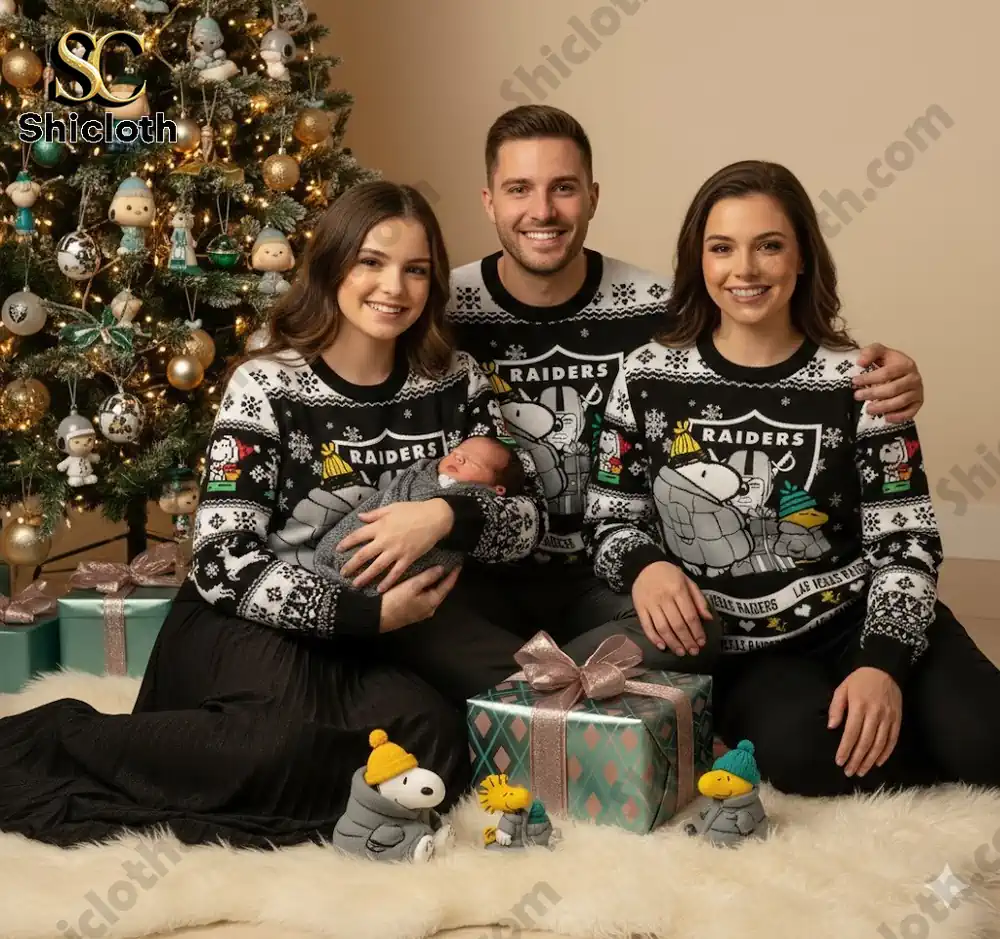 A family of three posing with a Christmas tree while wearing matching Peanuts Snoopy sweaters featuring the Las Vegas Raiders logo and characters.
