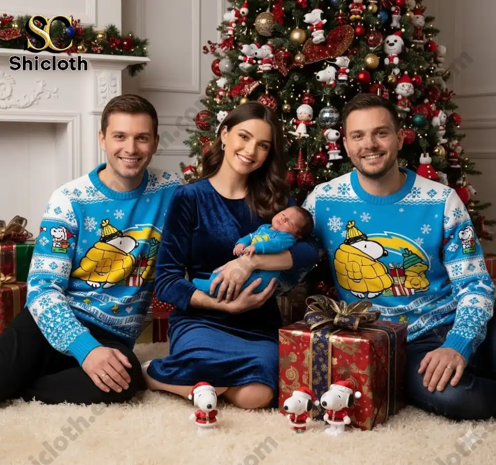 A family of three, wearing Snoopy-themed sweaters, sits on the floor with Christmas decorations and presents around them.
