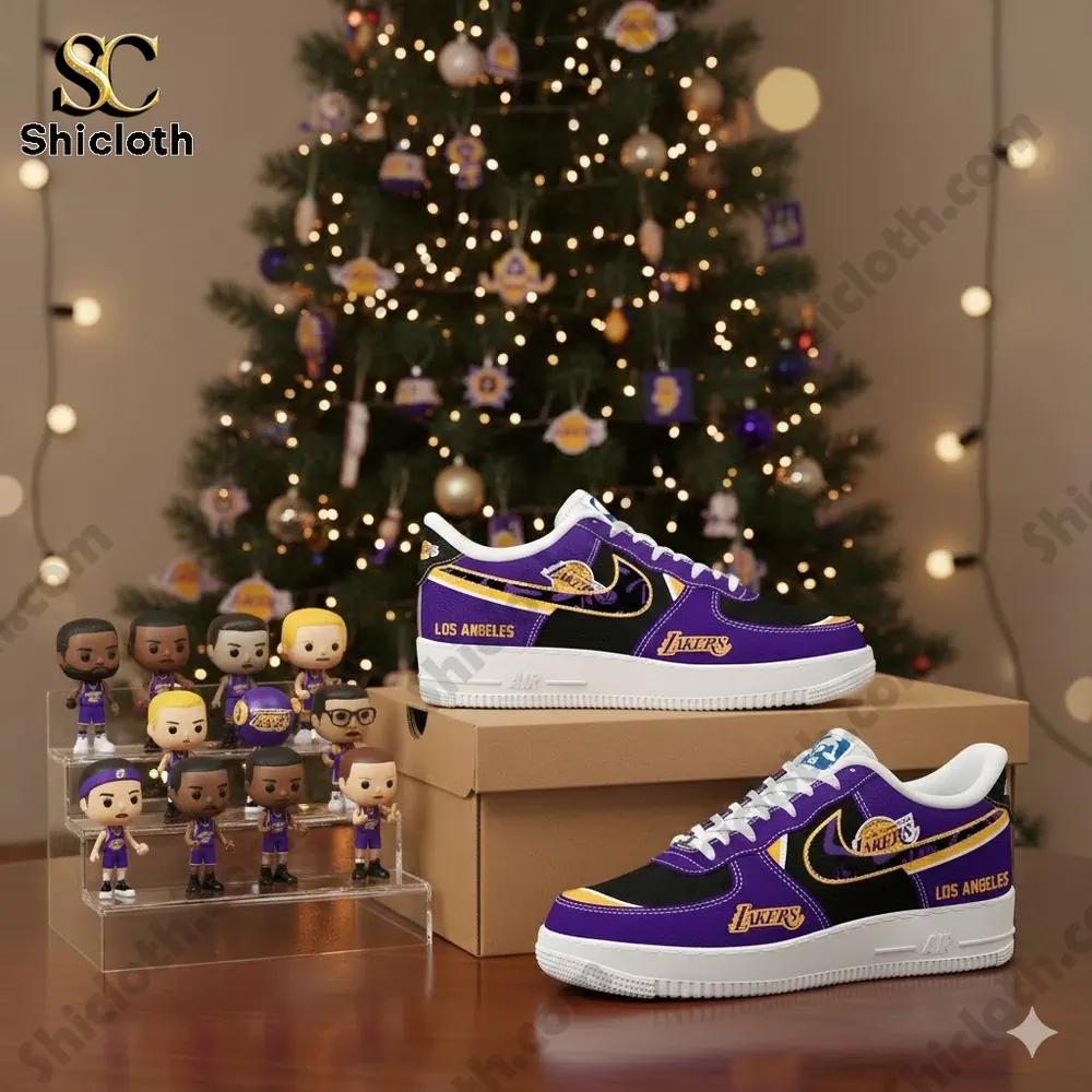 Purple and black Los Angeles Lakers themed sneakers displayed on a box in front of a decorated Christmas tree with small figurines beside them.