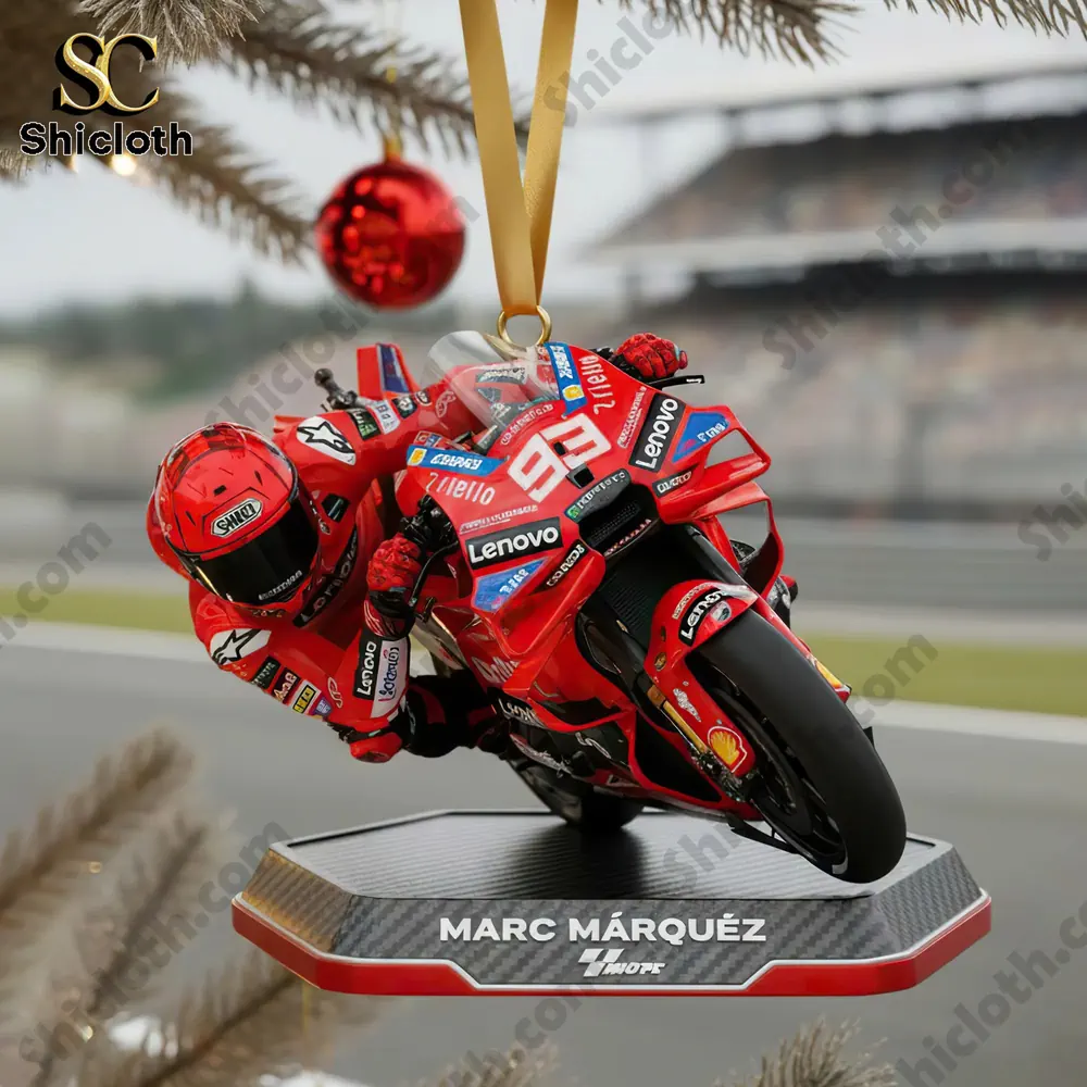 A close-up of a Marc Marquez MotoGP rider ornament hanging on a Christmas tree with a red ball.