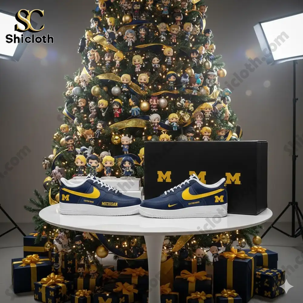 Blue and yellow Michigan themed sneakers displayed in front of a decorated Christmas tree with many small character ornaments.