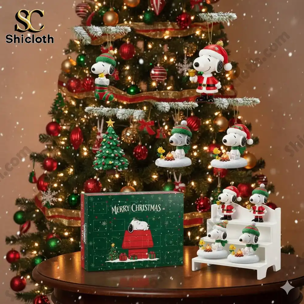 Snoopy Christmas ornaments and a Shicloth holiday box displayed before a decorated tree.