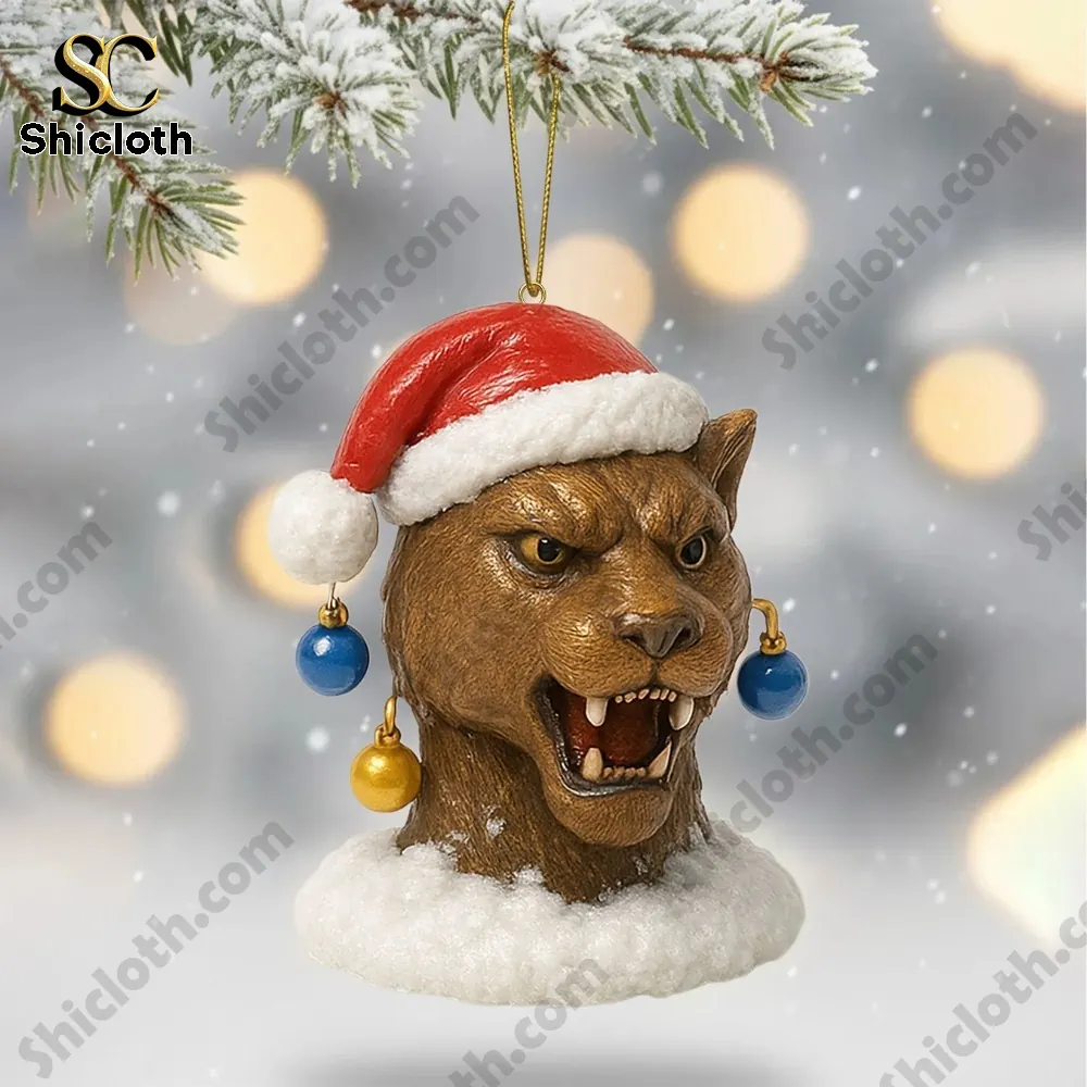 A fierce panther head ornament wearing a red Santa hat hanging from a snowy branch.