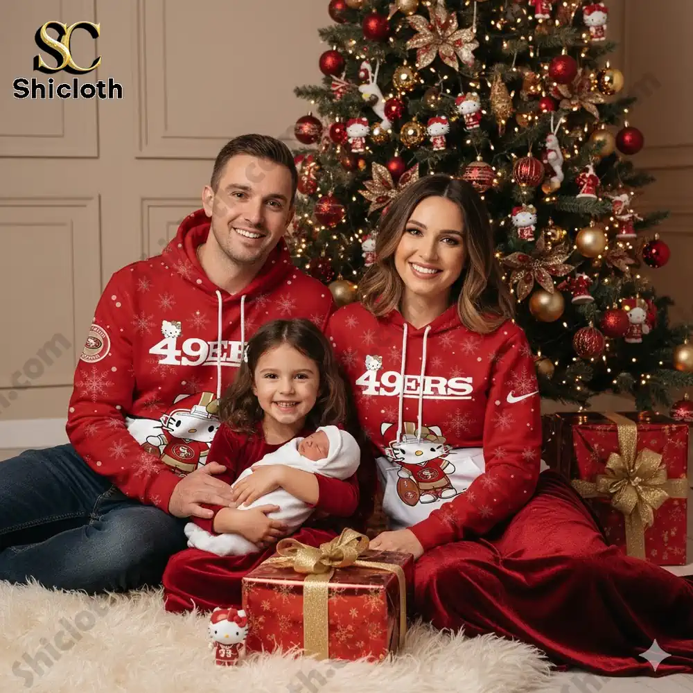 Family wearing matching San Francisco 49ers Hello Kitty Christmas hoodies, posing in front of a decorated tree with gifts.
