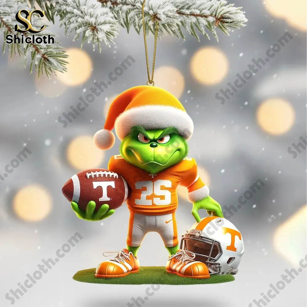 A green Grinch figure wearing Tennessee Volunteers gear holding a football ornament.
