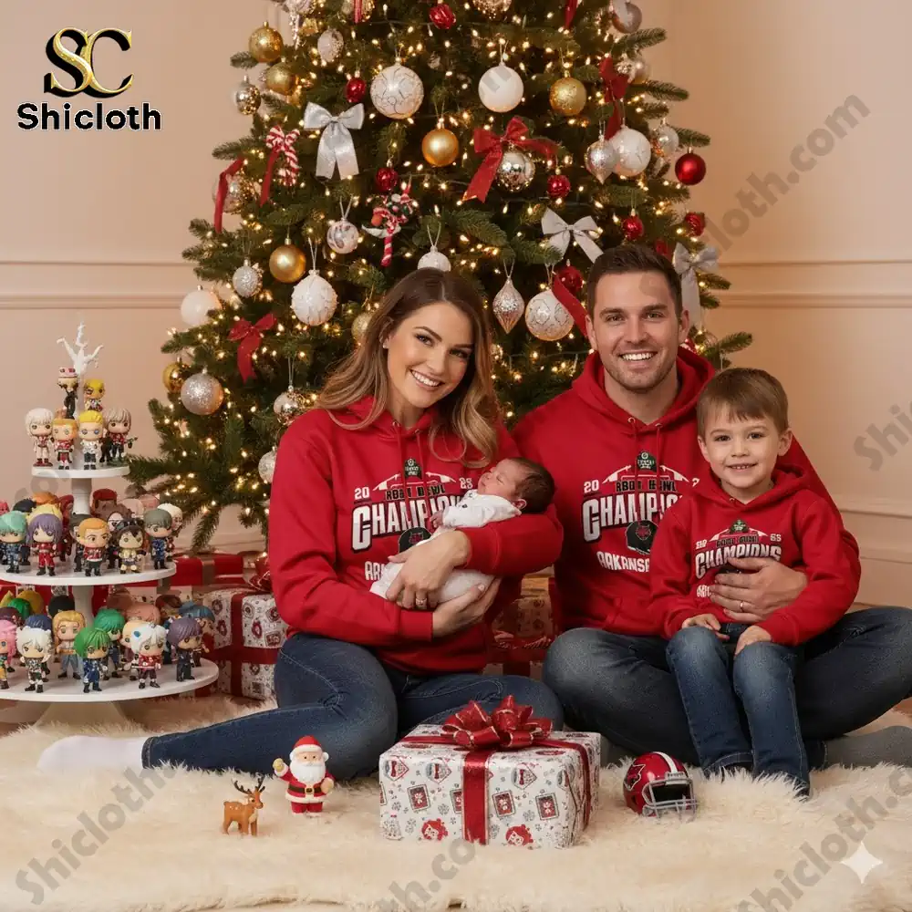 A family wearing matching red Arkansas State Champions hoodies poses by a Christmas tree with gifts and collectibles!