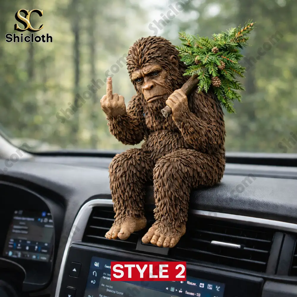 Bigfoot figurine on a car dashboard raising one finger and holding a pine branch!