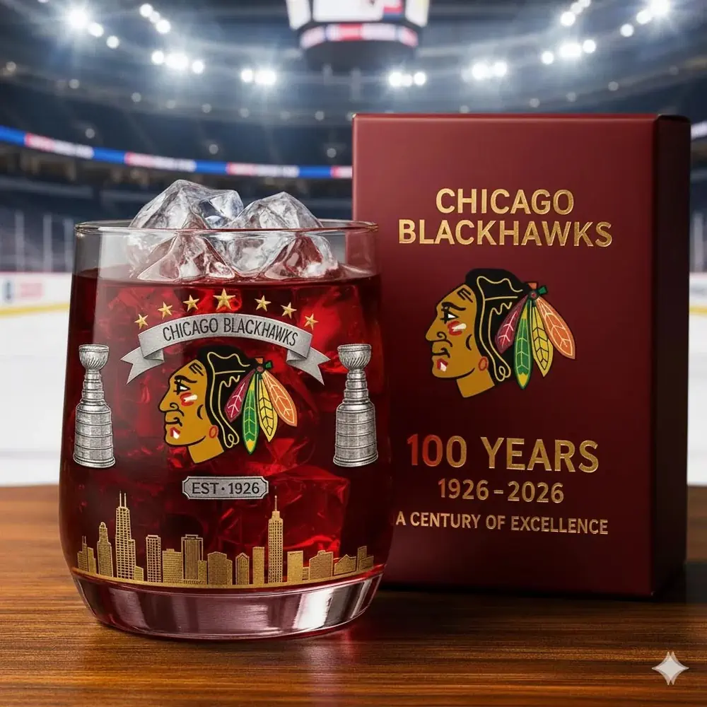 Chicago Blackhawks 100th Anniversary Christmas Whiskey Glass 3 A Chicago Blackhawks centennial glass filled with ice sits next to its commemorative box inside a hockey arena.