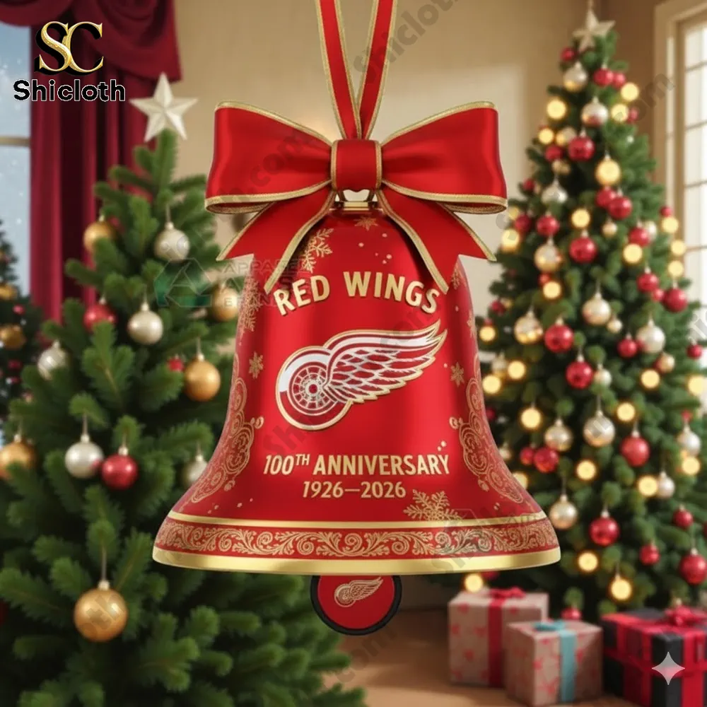 A red bell ornament with a bow featuring the Red Wings anniversary theme hanging on a Christmas tree.