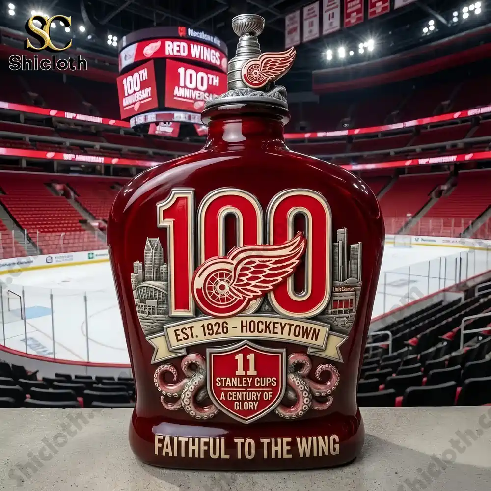 Red Wings 100th Anniversary commemorative bottle in front of an empty hockey arena with banners celebrating the anniversary.