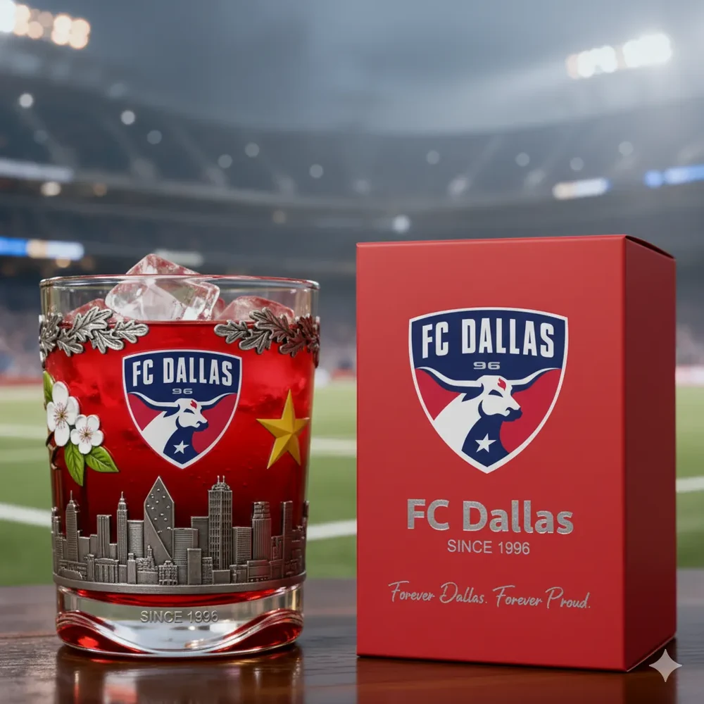 FC Dallas Christmas Whiskey Glass 3 A red drink in an FC Dallas themed glass beside its decorative box in a stadium environment!