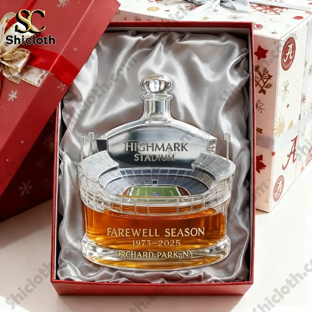 A commemorative whisky bottle shaped like a stadium with a clear base and detailed stadium design, including a football field inside, labeled "Highmark Stadium - Farewell Season 1973-2025, Orchard Park, NY."