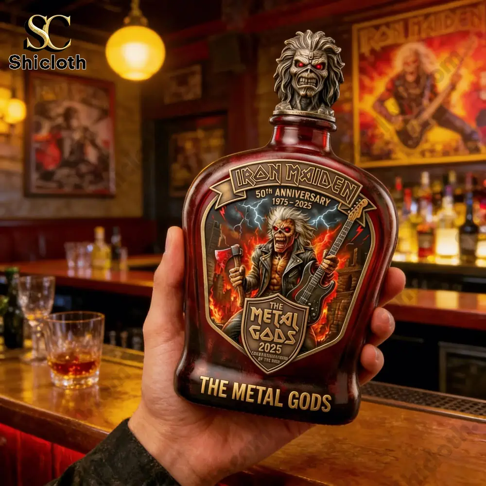Iron Maiden 50th Anniversary The Metal Gods whiskey bottle held in a hand in a bar with Iron Maiden posters in the background.