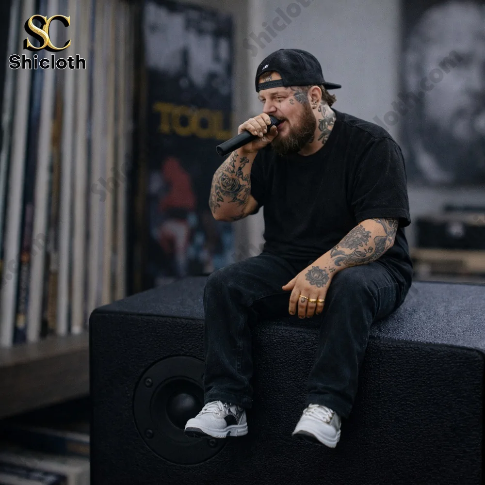 Tattooed man holding microphone sitting on large speaker!