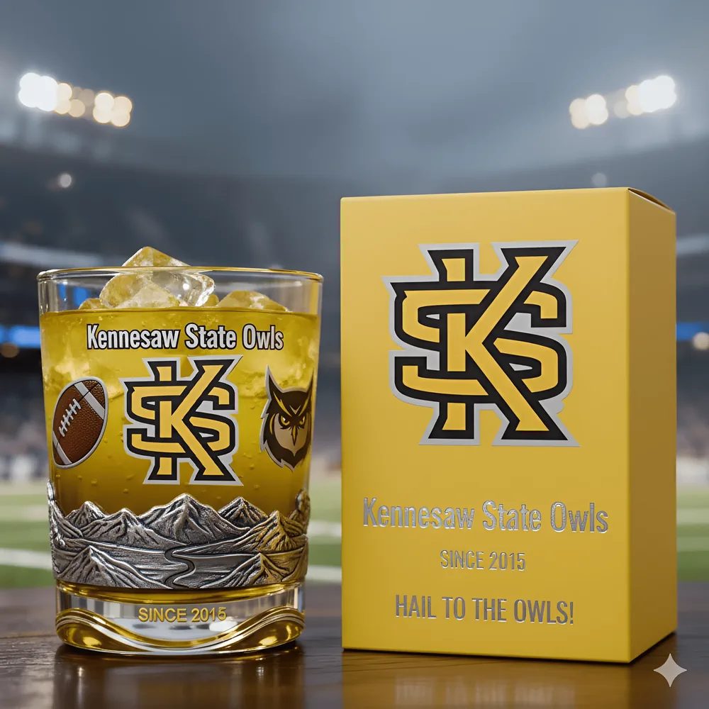 Kennesaw State Owls Christmas Whiskey Glass 3 Owls themed glass with ice next to a bright yellow Shicloth box in a stadium scene!