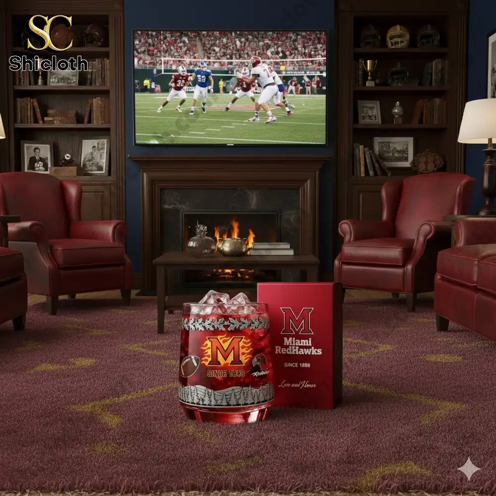 A cozy room with Miami RedHawks-themed decor, featuring a football game on the TV, a festive candle, and comfortable red chairs.