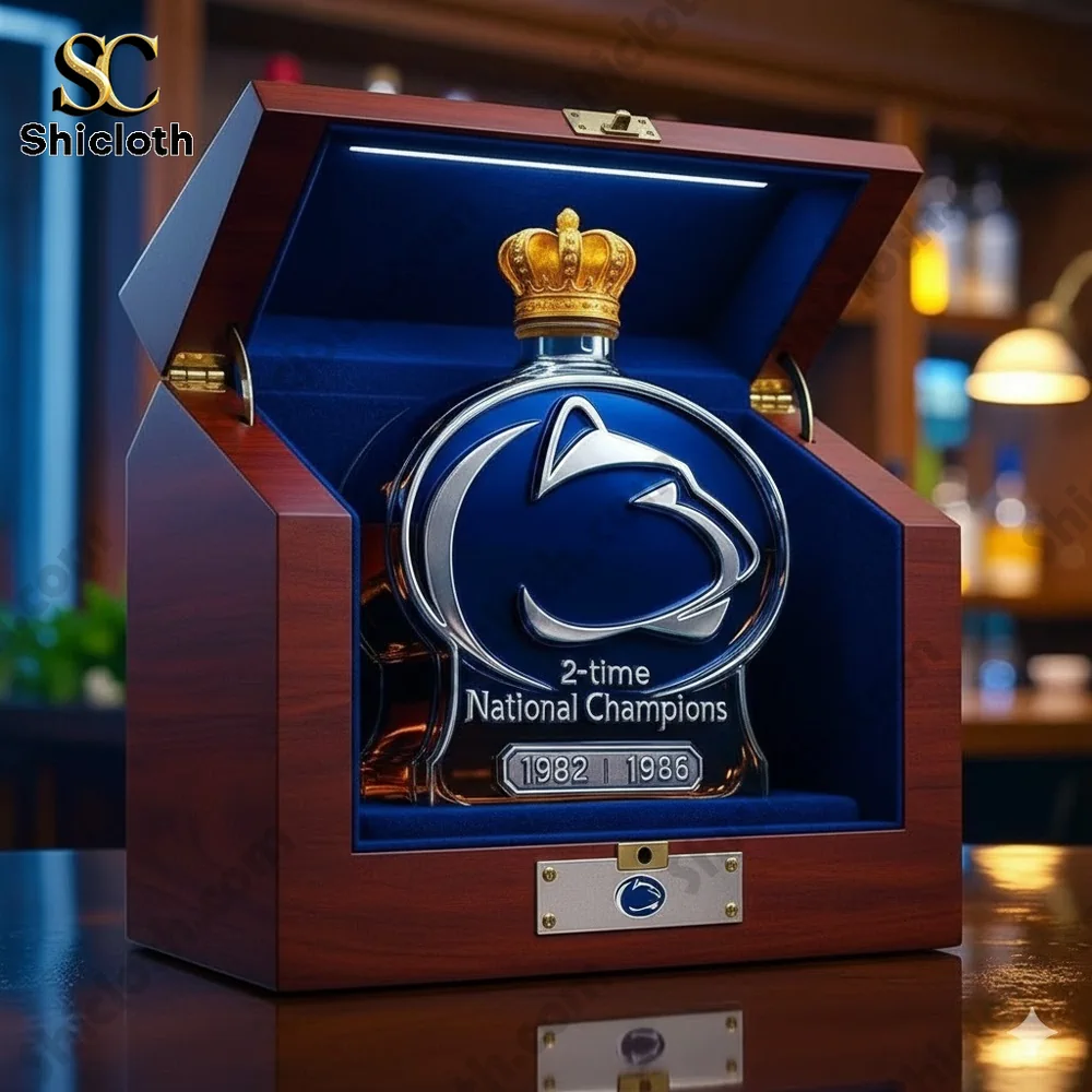 A wooden display case with a whiskey bottle in the shape of a football helmet, featuring the Penn State Nittany Lions logo and a crown, commemorating the team's 2-time National Championships in 1982 and 1986.