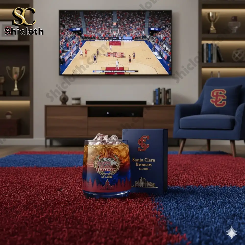A glass with Santa Clara Broncos design on a rug in a living room with a basketball game on a television screen.