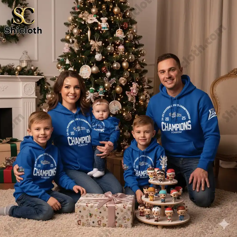 A family in blue champion hoodies posing by a Christmas tree with presents!