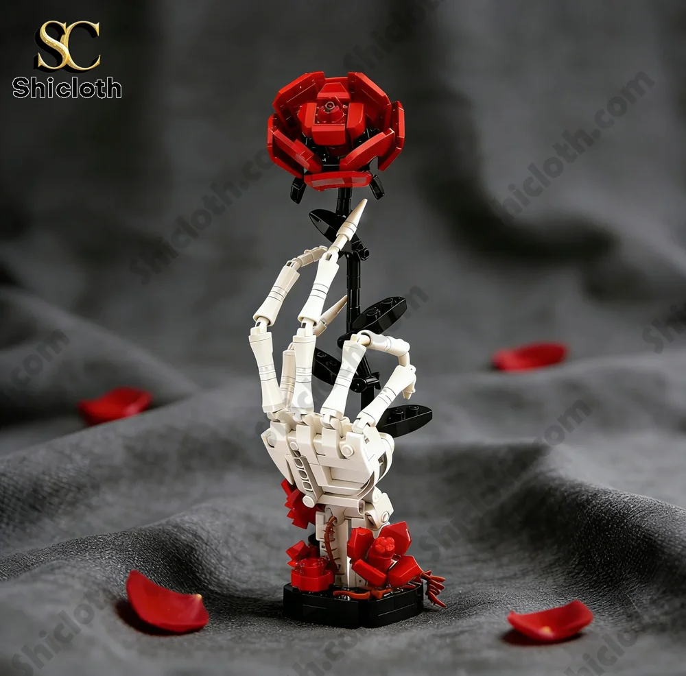 Skeletal hand holding a red rose made from building bricks on soft fabric background.