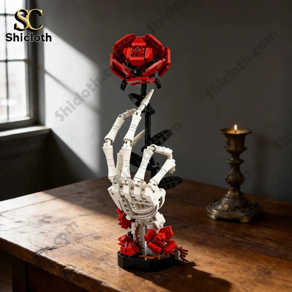 Skeletal hand holding a red rose made from building bricks on a wooden table with candle.