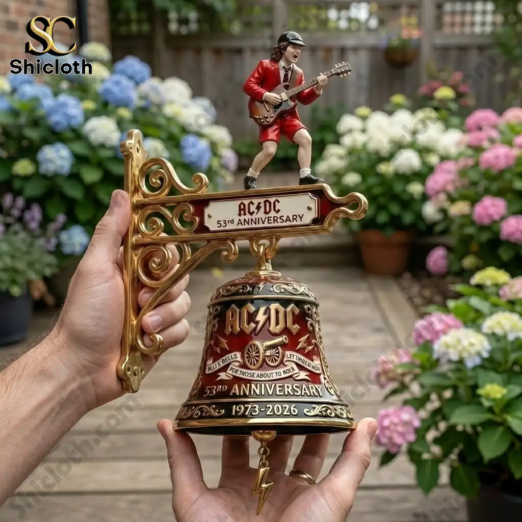 Hand holding AC DC 53rd Anniversary commemorative wall bell with Angus figure in garden!