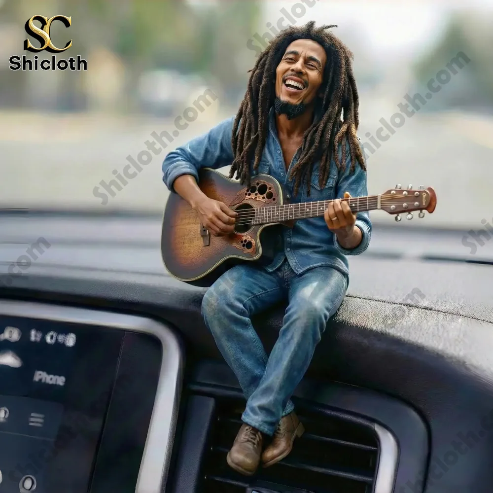 Smiling man with dreadlocks playing an acoustic guitar while sitting on a car dashboard.