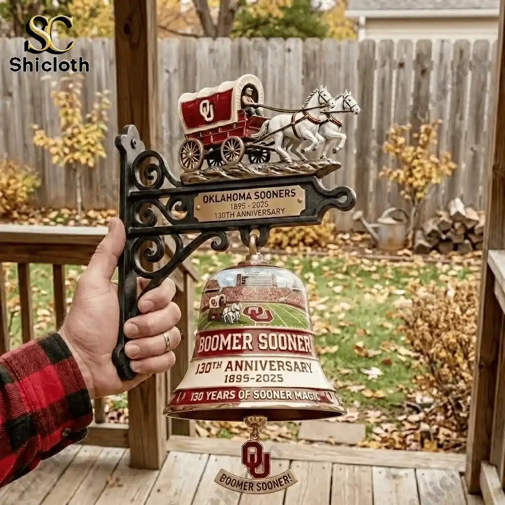 Hand holding Oklahoma Sooners 130th Anniversary commemorative wall bell on outdoor porch