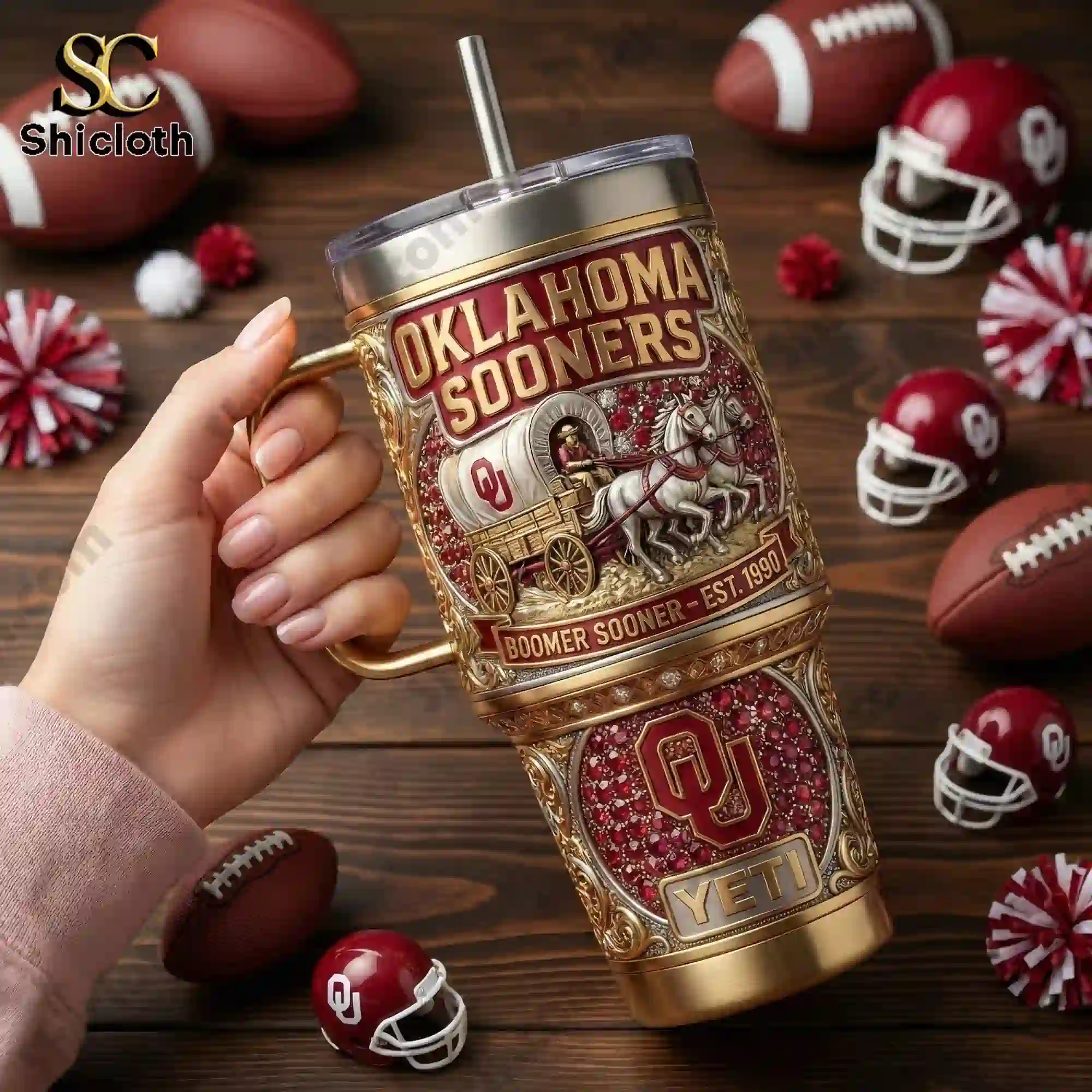 Oklahoma Sooners Boomer Sooner Limited Edition 40oz Tumbler with Handle 3 Hand holding an Oklahoma Sooners tumbler mug with football themed background.
