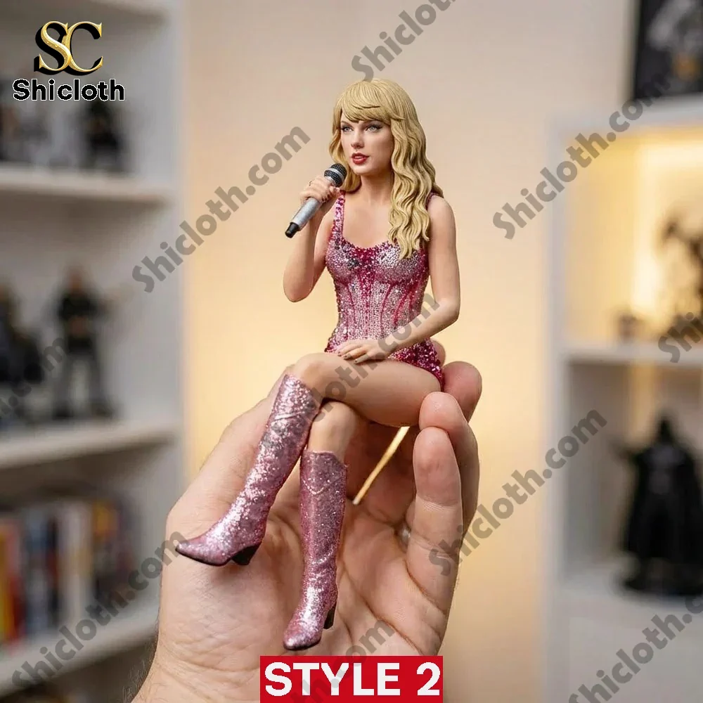Taylor Swift style pink dress figurine sitting on a hand holding a microphone.