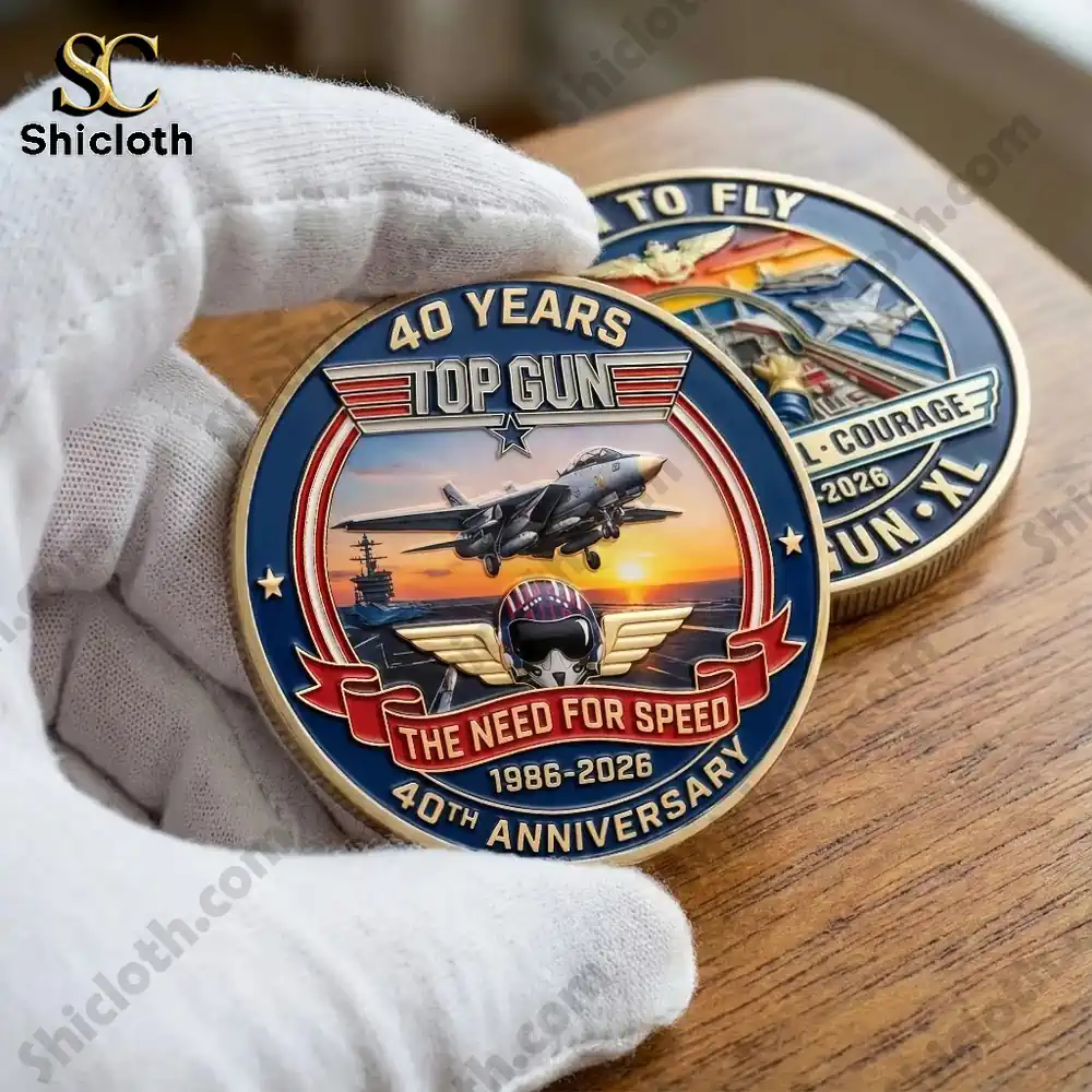 Gloved hand holding a Top Gun 40th anniversary commemorative coin on a wooden table.