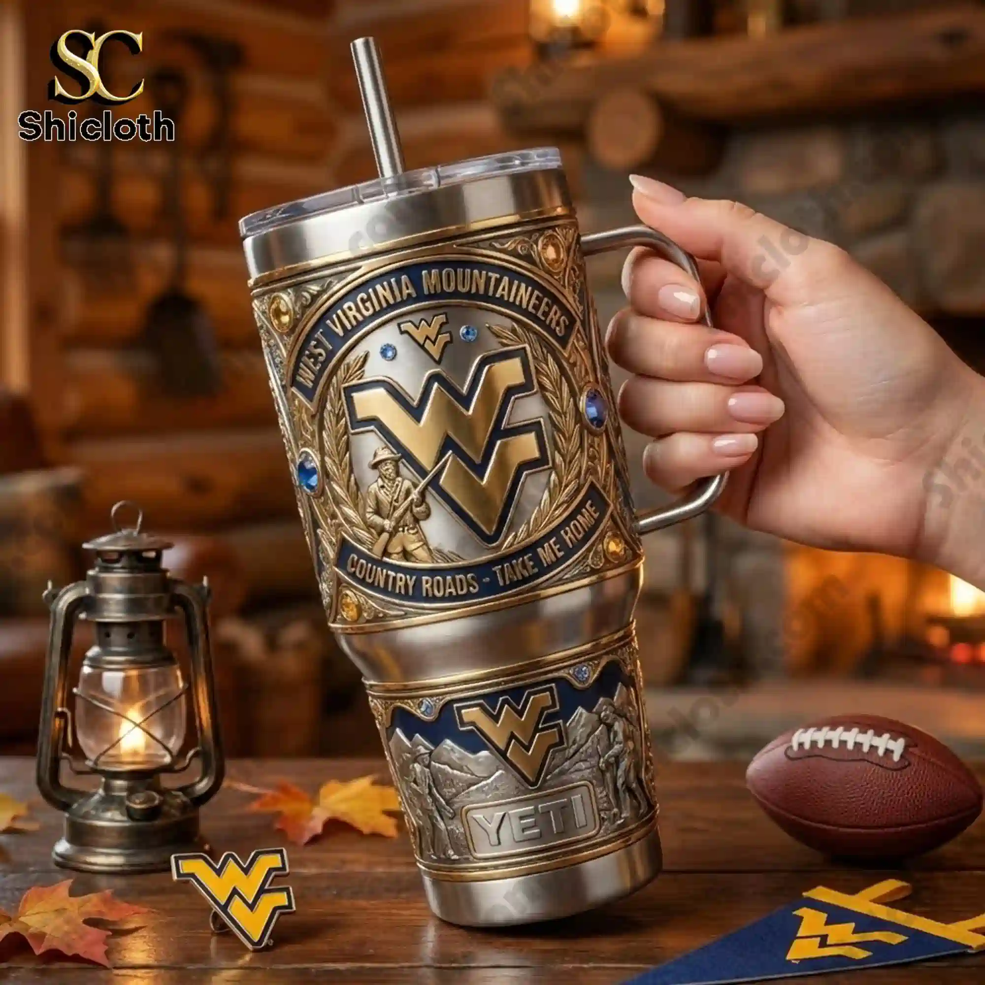 West Virginia Mountaineers 40oz Tumbler With Handle 3 Hand holding West Virginia Mountaineers tumbler inside a cozy cabin