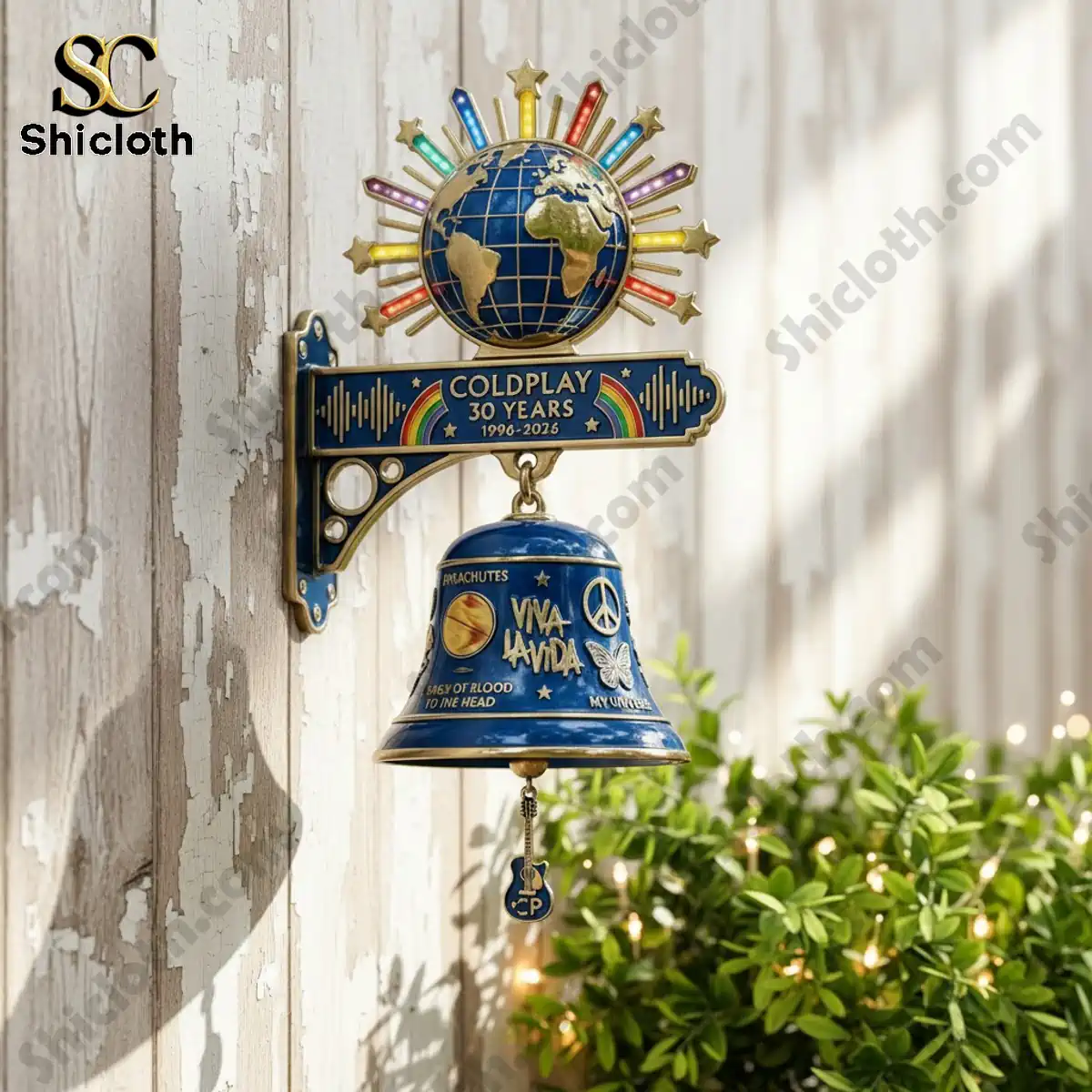 Coldplay 30 Years commemorative wall bell mounted on outdoor wall with green plants