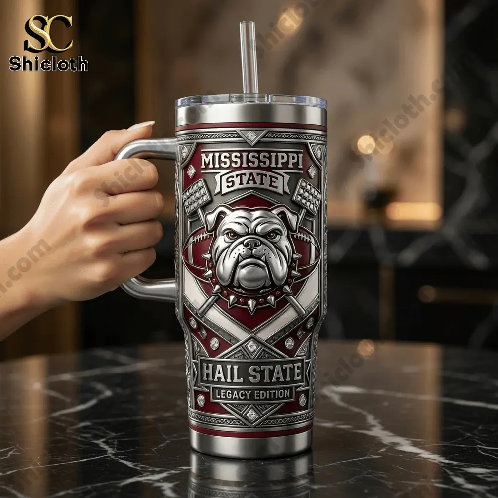 Hand holding Mississippi State insulated tumbler with bulldog logo in indoor setting.