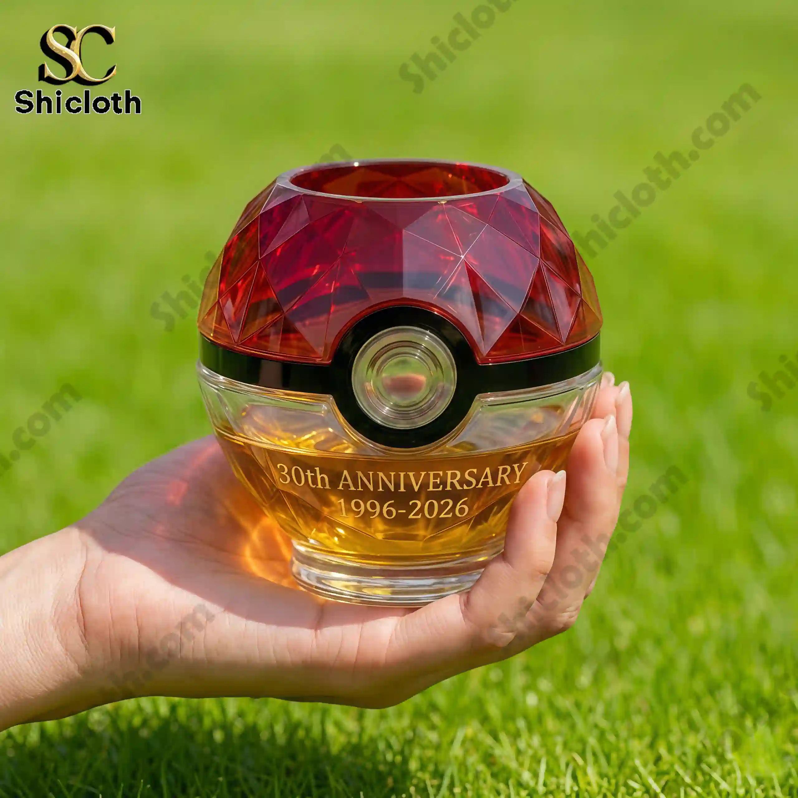 Close up of Pokemon thirtieth anniversary Pokeball whisky glass held in hand