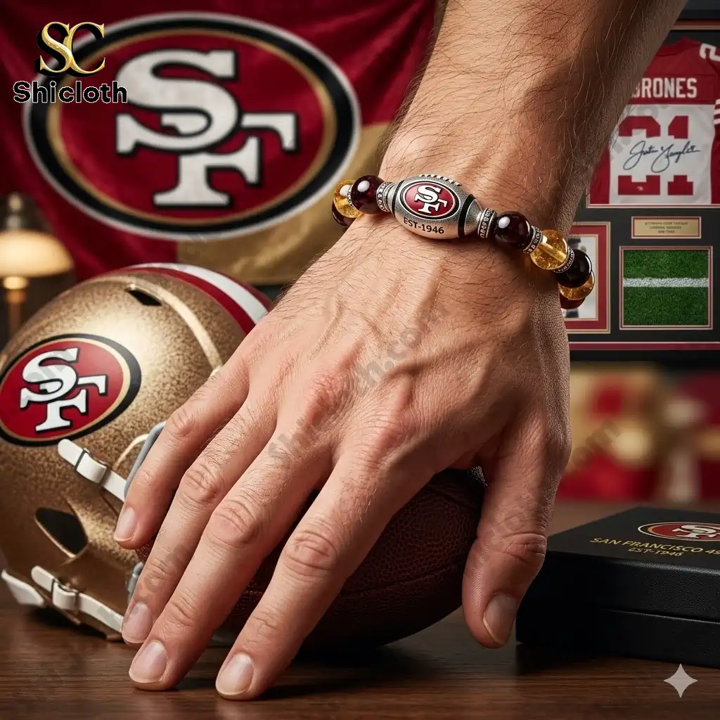 Hand wearing San Francisco Forty Niners bracelet resting on football and helmet!