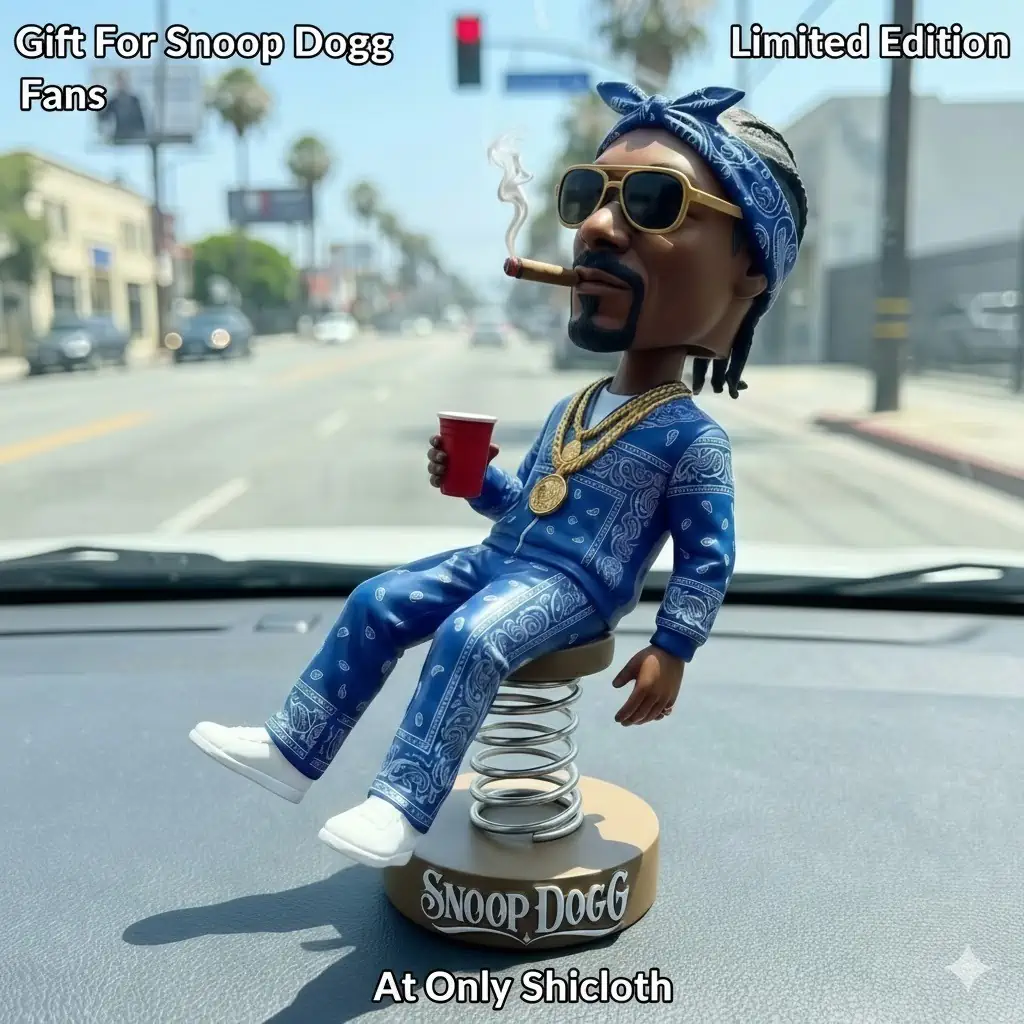 A bobblehead of Snoop Dogg with a blue tracksuit, holding a red cup and a cigar, sitting on a dashboard spring.