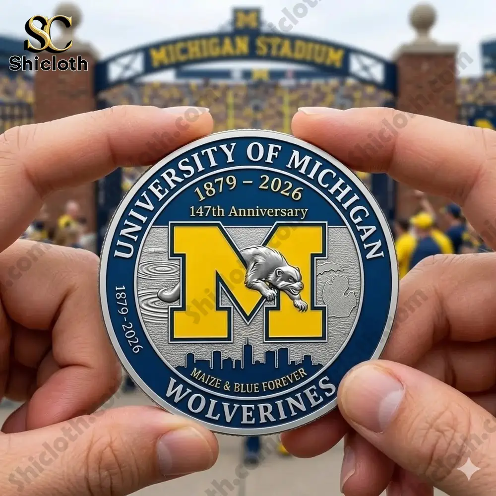 Hands holding University Michigan Wolverines anniversary coin in front of stadium crowd scene!