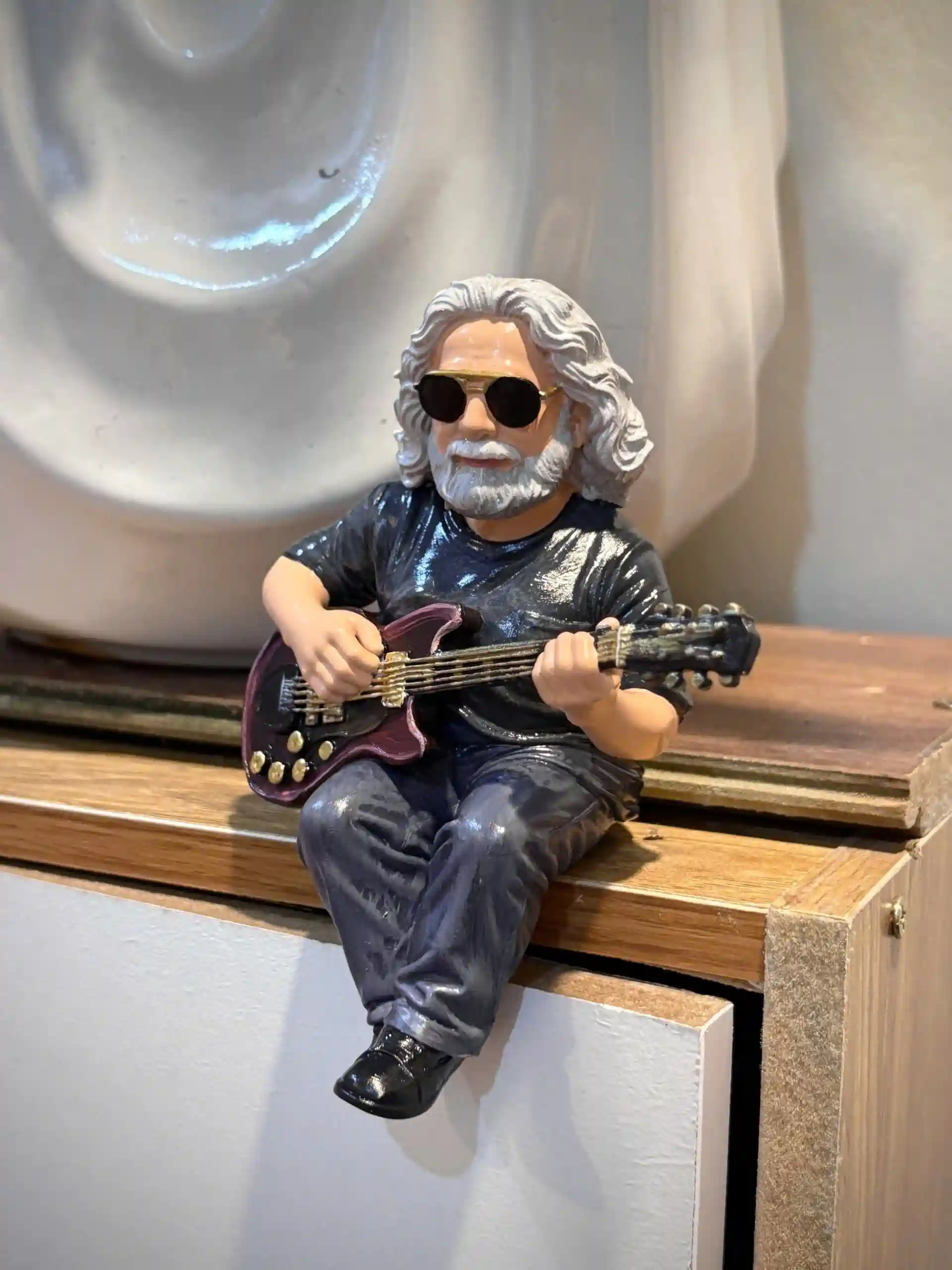 Miniature man with gray hair sunglasses playing guitar on wooden shelf!