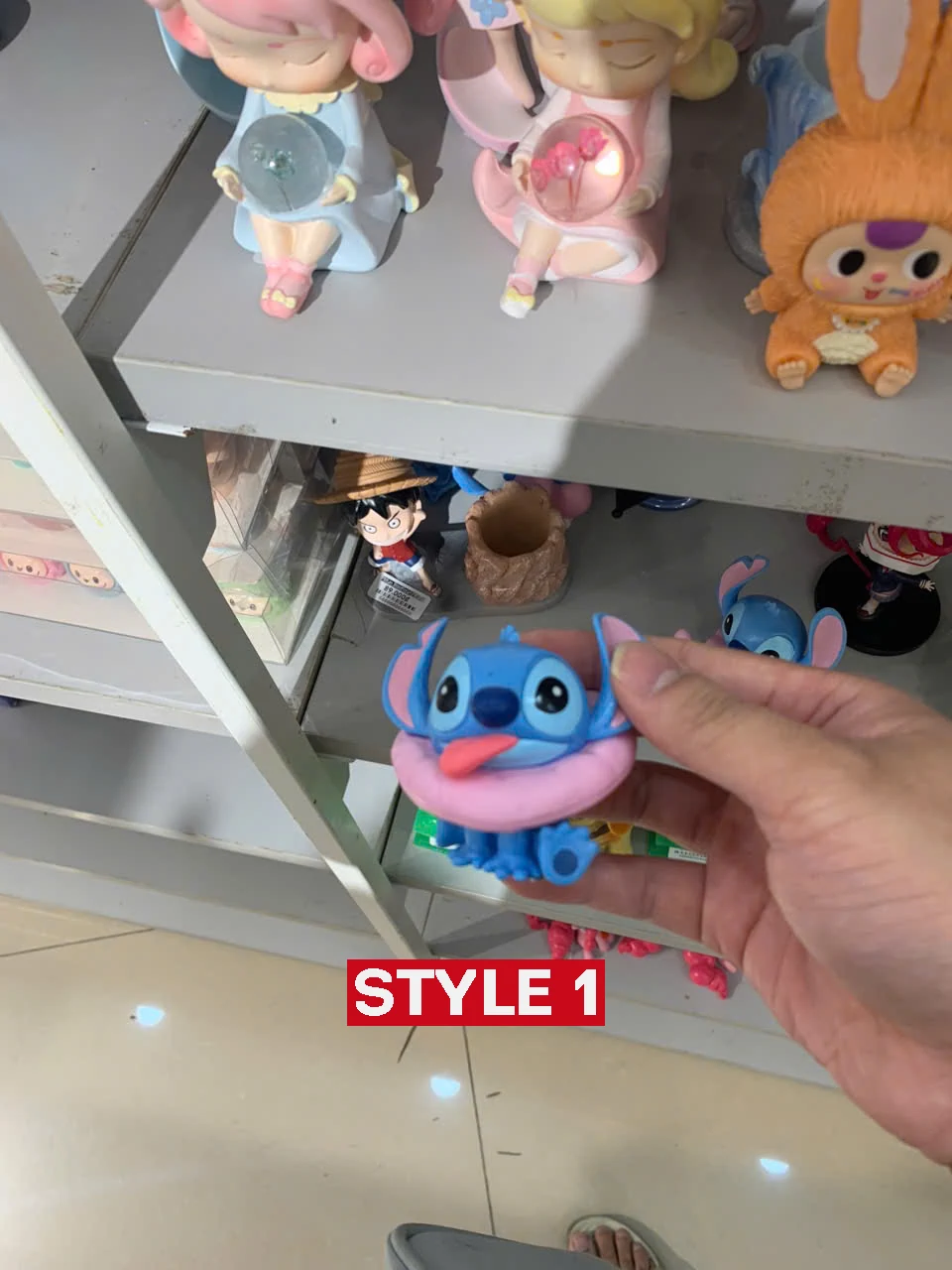 Hand holding Stitch figure style one near toy shelf display!